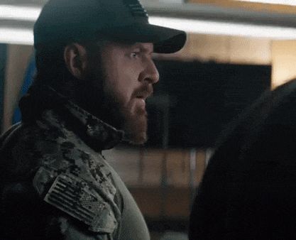a man in a military uniform is talking to another man in a room .