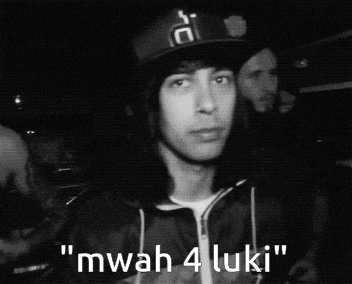 a man wearing a hat says " mwah 4 luki " in front of a group of men