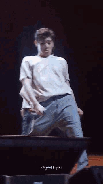 a man in a white shirt and blue pants is dancing on a stage with the words " the press 's gene " written below him