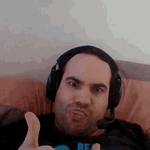 a man wearing headphones and a shirt that says re gives a thumbs up
