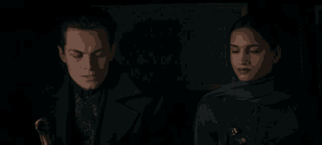 a man and a woman are looking at each other in a dark room