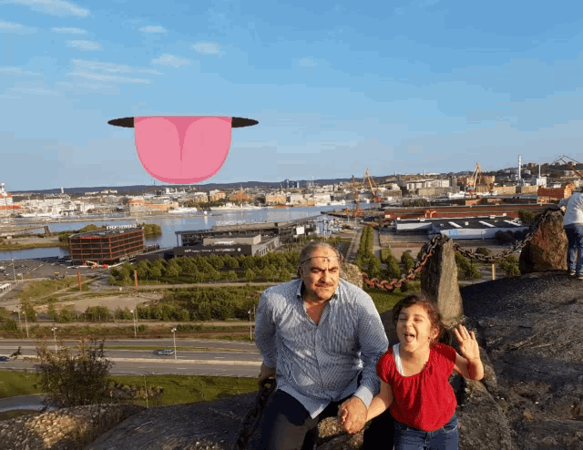 a man and a little girl are posing for a picture with a pink tongue flying in the sky