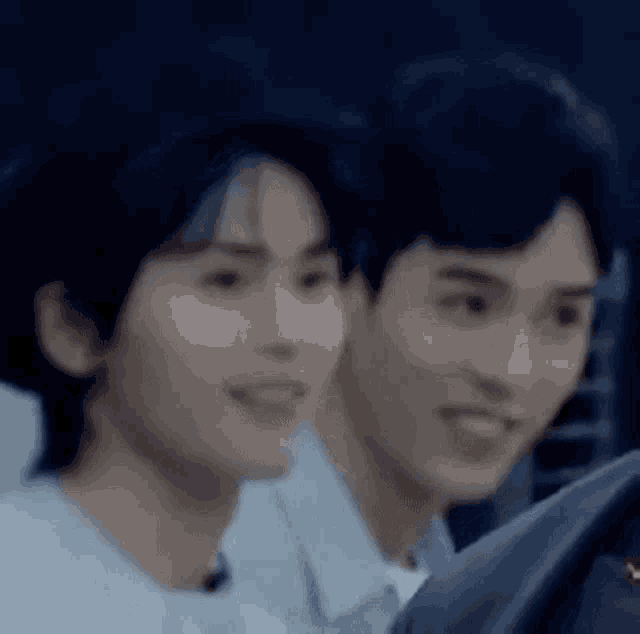 two young men are sitting next to each other and smiling at the camera .