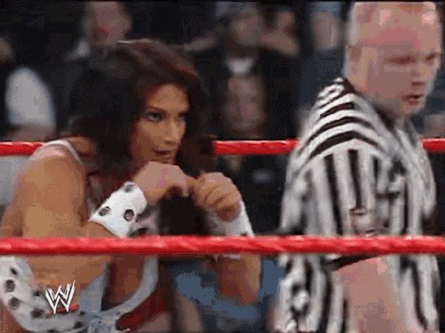 a woman is wrestling in a ring with a referee .