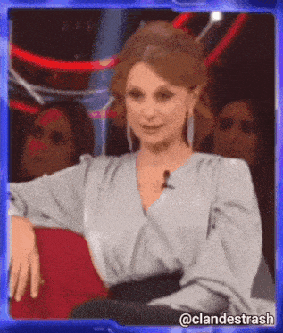 a woman is sitting in a chair with a microphone in front of her and a blue frame with the words clandestrash on it