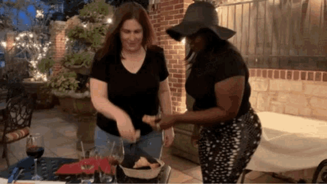 a woman wearing a black hat is standing next to another woman