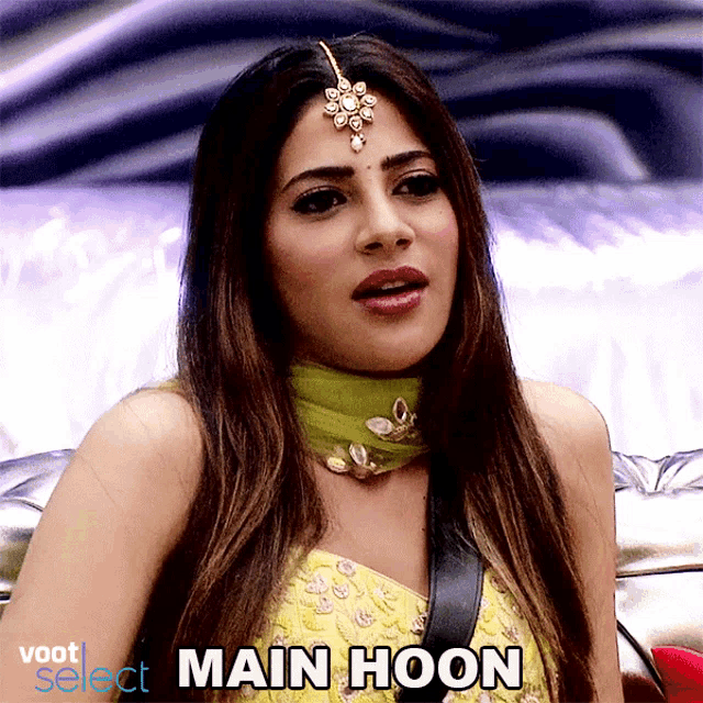 a woman wearing a green scarf and a yellow top with the word main hoon on the bottom