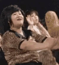 a woman in a leopard print shirt is sitting in front of a crowd of people .