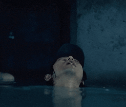 a man in a black hat is laying in the water with his eyes closed