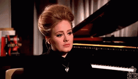 a woman is sitting in front of a piano and looking at the camera