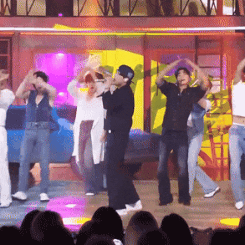 a group of people are dancing on a stage and one of them is wearing a hat