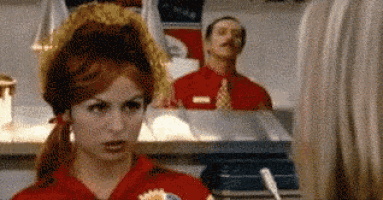 a woman in a red shirt is talking to a man in a red shirt in a fast food restaurant .