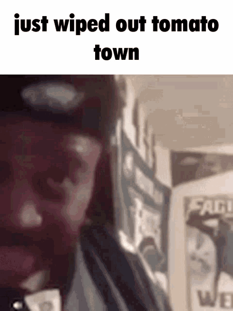 a man wipes out a tomato in a room with posters on the wall behind him