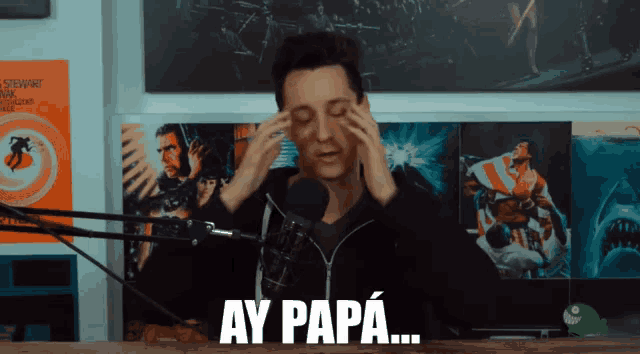 a man sitting in front of a microphone with ay papa written on his face
