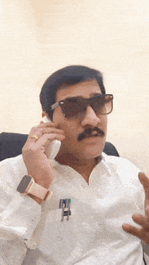 a man wearing sunglasses is talking on a phone