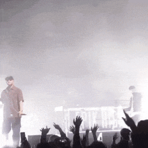 a man is standing on a stage holding a microphone in front of a crowd .