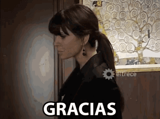 a woman stands in front of a painting with the word gracias on it