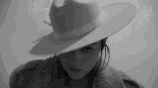 a black and white photo of a woman wearing a hat and a coat .