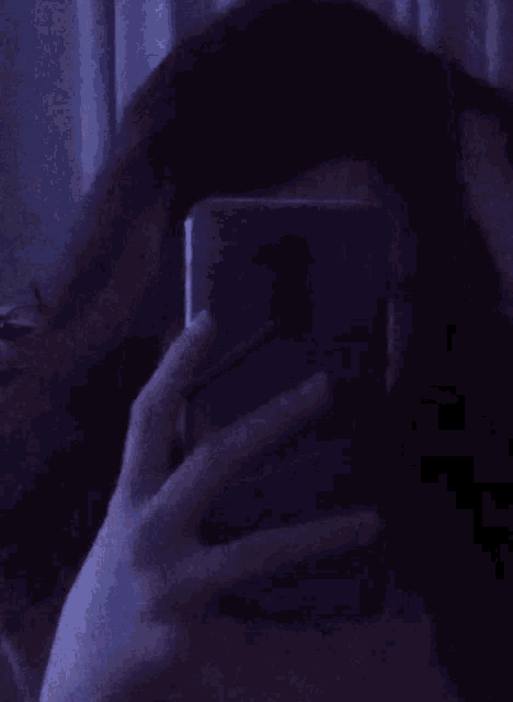 a person taking a selfie with their phone in a dark room