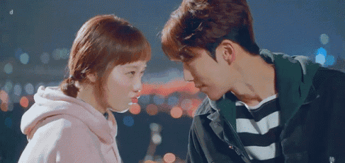 a man and a woman are looking at each other with a blurry background .