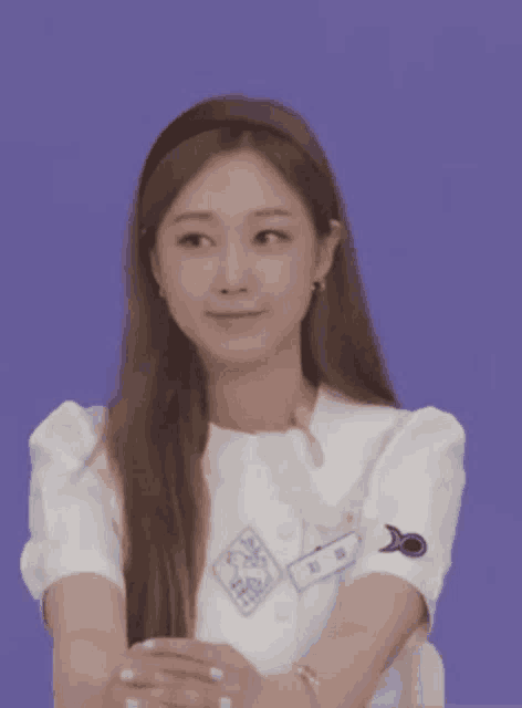 a woman wearing a headband and a white shirt is sitting with her hands folded .
