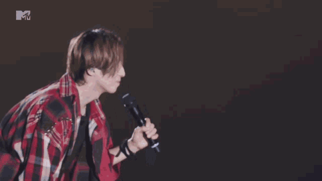 a man in a red plaid shirt is holding a microphone