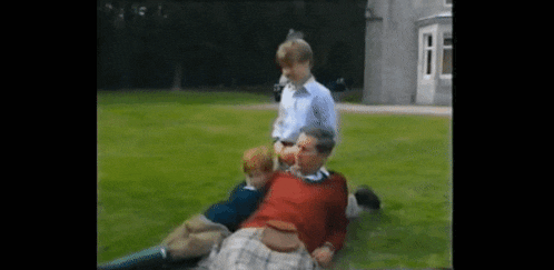 a man in a kilt is laying on the grass with two other men .