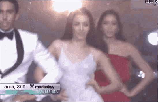 a man in a tuxedo and two women in red dresses are standing next to each other on a stage .