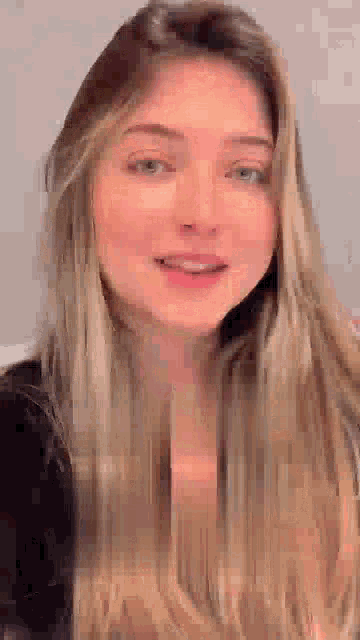 a woman with long blonde hair is smiling for the camera .