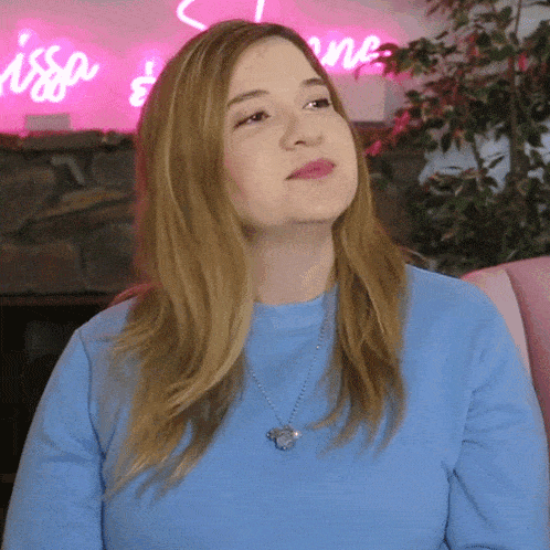 a woman in a blue shirt is sitting in front of a sign that says issa