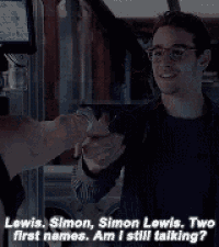 a man wearing glasses is shaking hands with another man and says lewis simon simon lewis two first names .