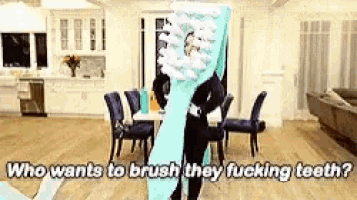 a man is holding a giant toothbrush in a living room .