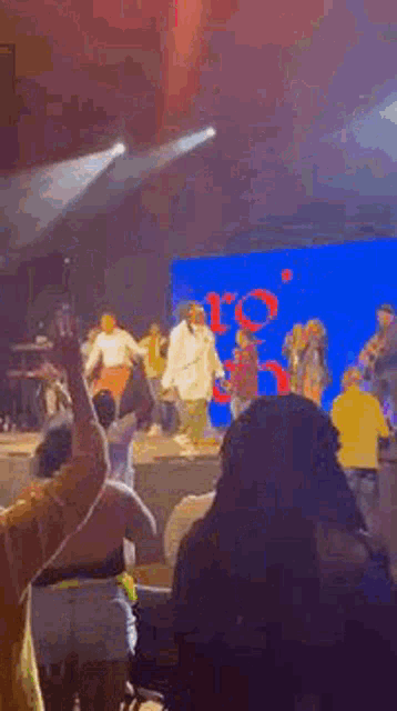 a group of people are standing on a stage in front of a large screen .