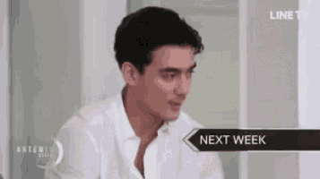 a man in a white shirt is sitting in front of a wall .