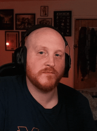 a bald man with a red beard wears headphones in front of a sign that says science on it