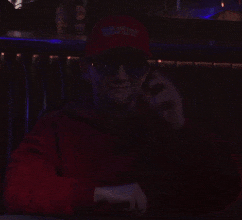 a young man wearing a red hoodie is holding a pair of sunglasses