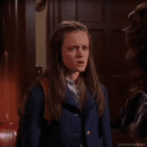 a girl in a blue jacket is making a funny face while standing next to another woman .