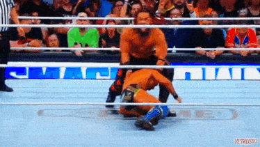a wrestling match is being held in a ring with a crowd watching .