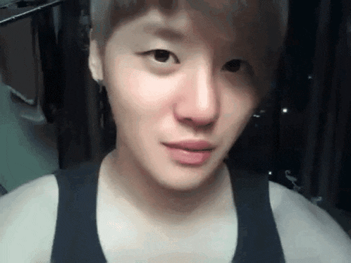 a close up of a person 's face with a black tank top