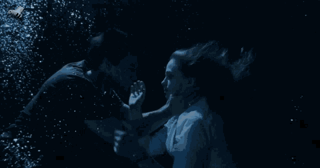 a man is holding a woman 's neck underwater