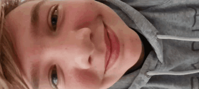 a close up of a person 's face wearing a grey hoodie with the letter j on it