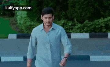 a man in a blue shirt is standing on the side of a road .