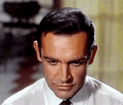 a close up of a man 's face with a white shirt and tie
