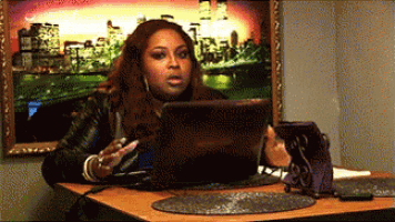 a woman is sitting at a table with a laptop and a phone