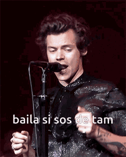 a man singing into a microphone with the words baila si sos de tam written on the bottom