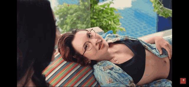 a woman wearing glasses is laying on a striped chair