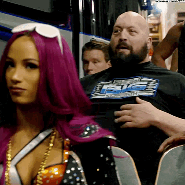 a woman with pink hair is standing next to a bald man wearing a shirt that says ' big show '