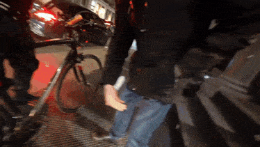 a man in a black jacket is standing next to a bicycle on a sidewalk