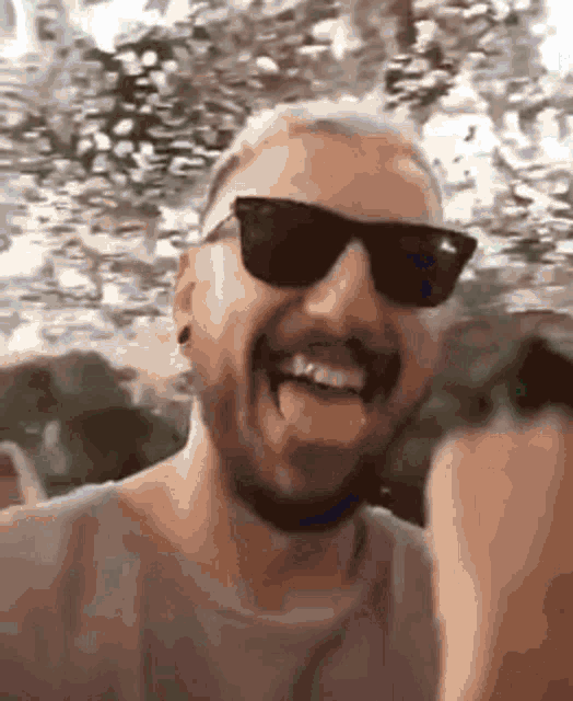 a man wearing sunglasses is sticking his tongue out while making a funny face .