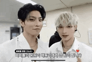 two young men are standing next to each other in a room and looking at each other .